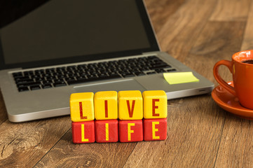 Live Life written on a wooden cube in a office desk