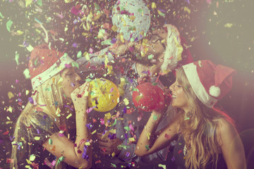 Three young people at New Year's Eve party on midnight blowing colorful balloons and having fun