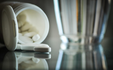 pile of prescription pills and glass of water