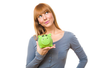 Beautiful daydreaming and holding a green piggy bank isolated on white background