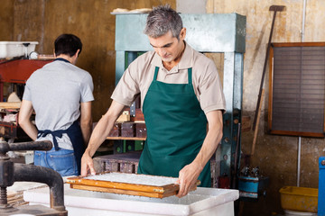 Worker Dipping Mold In Pulpy Water At Paper Factory