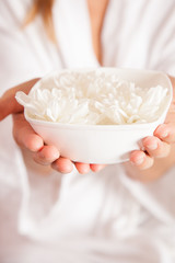 Woman holding a bowl of withe flowers