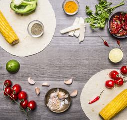Ingredients for cooking vegetarian burritos lined frame, with various vegetables and spices with space for text on grey wooden rustic background top view