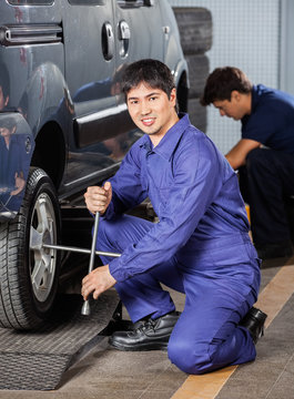 Mechanic Fixing Car Tire With Rim Wrench At Workshop