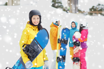 happy friends in helmets with snowboards