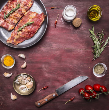 Ingredients for cooking raw lamb ribs in a pan with herbs, a knife, seasoning, tomatoes place for text,frame on wooden rustic background top view