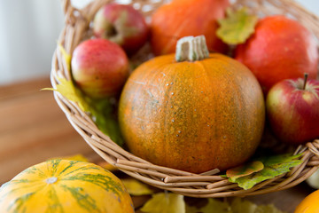 close up of pumpkins in basket on wooden table