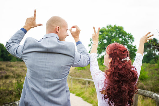 Newlywed Couple Spelling The Word Love With Their Hands