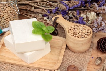 Tofu and soybeans on wood background.