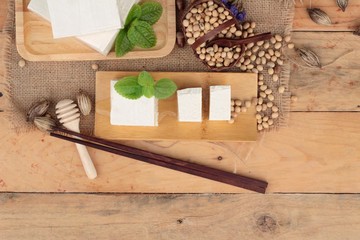 Tofu and soybeans on wood background.