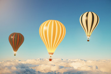 Three balloons above the clouds at sunset