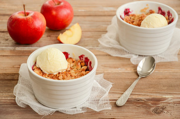Apple and black currant crumble with ice cream on rustic wooden table