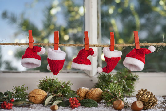 Weihnachtlicher Hintergrund mit typischer Nikolausmütze auf einer Wäscheleine vor Landhausfenster