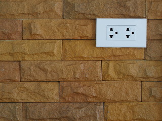 White outlet mount on brown stone wall