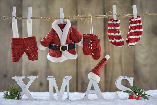 Weihnachtlicher Hintergrund mit Nikolausbekleidung auf der Wäscheleine und Holzbuchstaben XMAS