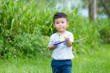 Asian little boy playing tennis at park