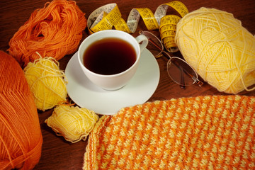 Woolen yarn, knitting,cup of tea, glasses and measuring tape 