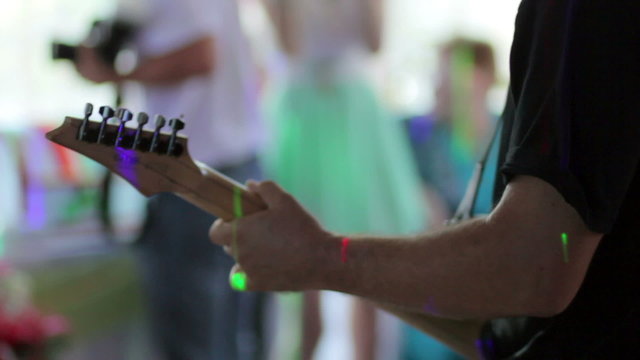 The man playing the guitar at the festival.  View from back.