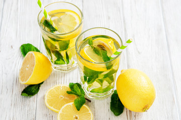 
iced tea with lemon, mint and ginger on a wooden background