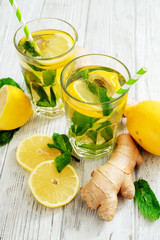 
iced tea with lemon, mint and ginger on a wooden background
