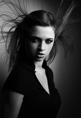 Wild expressive woman with wind hairstyle and vamp look on dark.