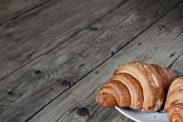 Two croissants on a plate in the foreground on table