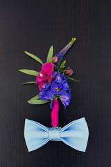 boutonniere and bowtie on a wooden table