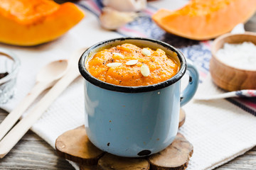 Autumn pumpkin soup in a blue mug, rustic background