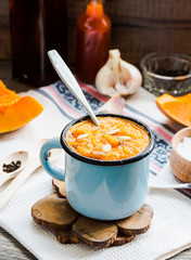 Autumn pumpkin soup in a blue mug, rustic background,selective f