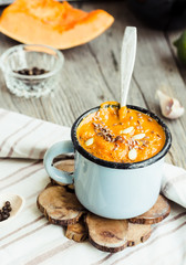 Autumn pumpkin soup in a blue mug, rustic background
