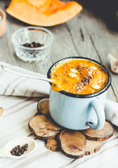 Autumn pumpkin soup in a blue mug, rustic background,tinting