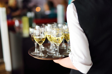 Waitress with dish of champagne and wine glasses