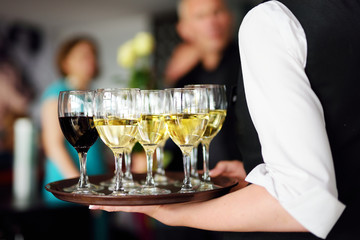 Waitress with dish of champagne and wine glasses