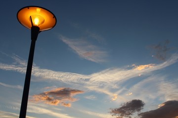 Abendstimmung mit einer Laterne im Vordergrund vor leicht bewölktem Himmel im Sonnenuntergang