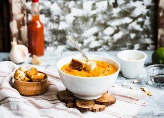 Pumpkin soup with carrots, croutons in a white dish, vegetarian