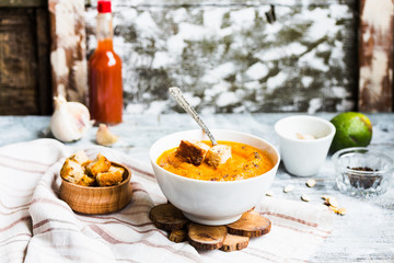 Pumpkin soup with carrots, croutons in a white dish, vegetarian