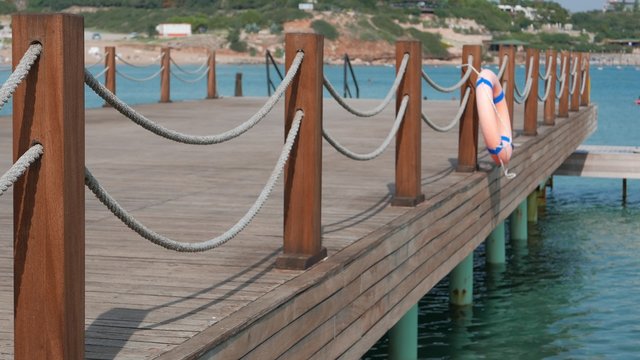 Scene of calm bathing place with emty wooden stage with ropes and lifebuoy and sea background. 4k