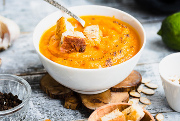 Pumpkin soup with carrots, croutons in a white dish, vegetarian