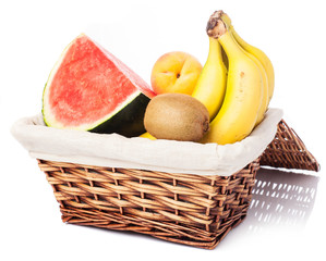 wicker basket with bananas, melon, kiwi and peach