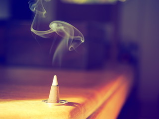 Incense cone on a wooden table in the sunshine shot with a vintage filter
