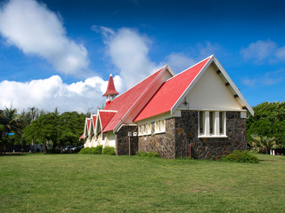 Fototapeta na wymiar Church Notre Dame Auxiliatrice with green grass and a blue sky. Situated in the northern part of Mauritius
