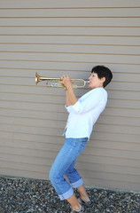 Female beauty blowing her trumpet loudly outside.