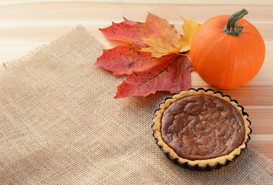 Small pumpkin pie with gourd and autumn leaves