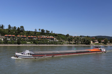 Obraz premium Cargo barge drifting on the river near the scenic shores