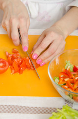 Girl cuts a tomato for a vegetable salad