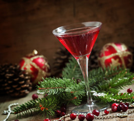 Red Christmas cocktail in a martini glass with fir branches, pin
