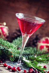 Red Christmas cocktail in a martini glass with fir branches, pin