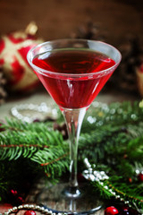 Red Christmas cocktail in a martini glass with fir branches, pin