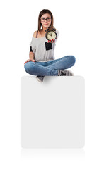 young woman holding an alarm clock sitting on a white box