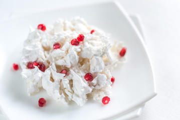 Portion of meringue with pomegranate seeds